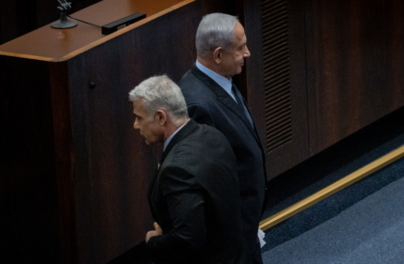  Prime Minister Benjamin Netanyahu and Opposition Leader Yair Lapid pass each other in the Knesset plenum, February 27, 2023. (credit: OREN BEN HAKOON/FLASH90)