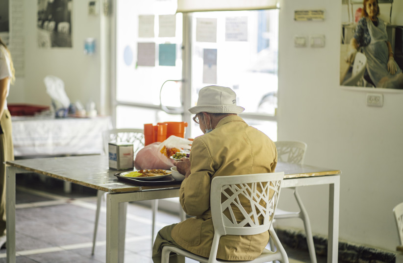 Elderly man receiving cooked food from Leket Israel NPO partner (credit: AMIR YAKOBY)