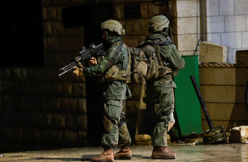  Israeli troops stand guard at the scene of a shooting, in Huwara, in the West Bank, March 19, 2023. (photo credit: MOHAMAD TOROKMAN/REUTERS)