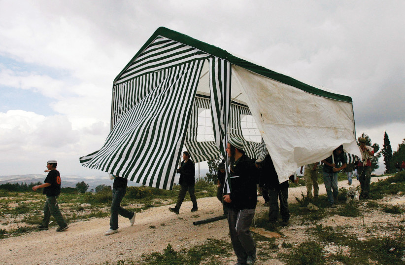  ISRAELI ACTIVISTS carry a tent in the abandoned settlement of Homesh, in 2007.  (photo credit: RONEN ZVULUN/REUTERS)
