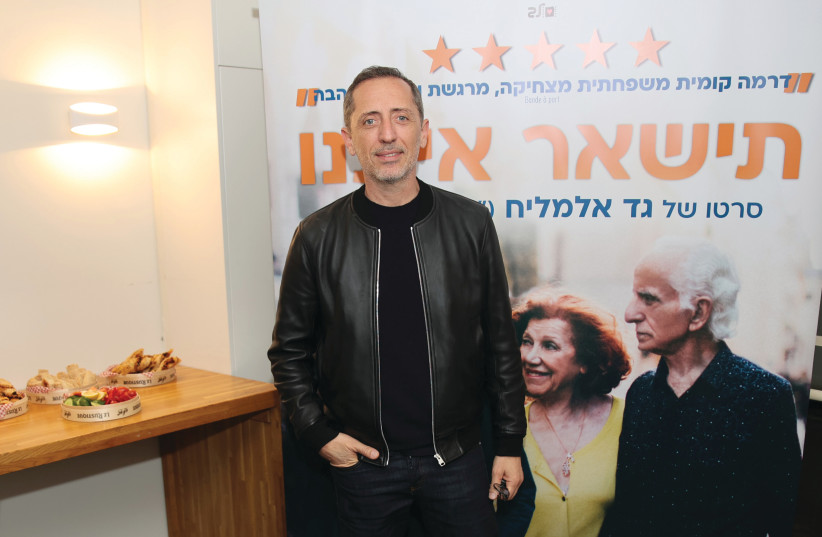  GAD ELMALEH in front of a poster promoting his movie ‘Stay With Us.’  (photo credit: LEV CINEMAS, OR GHEFEN)