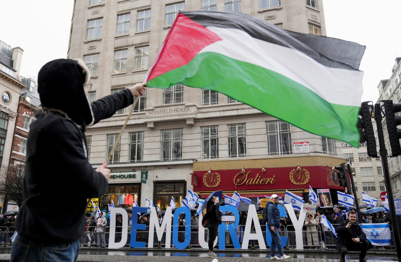  A demonstrator waves a Palestinian flag near demonstrators with Israeli flags during a protest against Israeli Prime Minister Benjamin Netanyahu and the government's judicial reform plans as he visits Britain, in London, Britain March 24, 2023. (credit: REUTERS/Maja Smiejkowska)