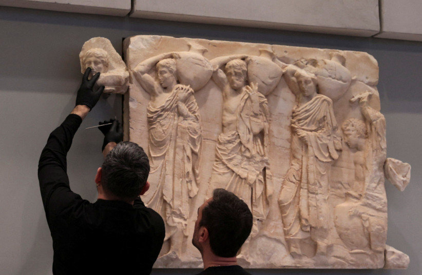  A conservator holds one of three Parthenon fragments, returned from the Vatican, at the Parthenon Gallery of the Acropolis Museum, in Athens, Greece March 24, 2023. (photo credit: REUTERS/LOUIZA VRADI)