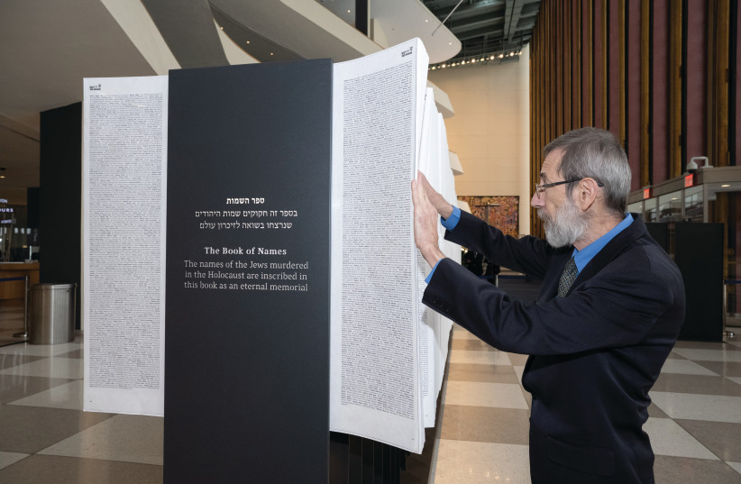  THE WRITER leafs through the pages of the Book of Names on display at the United Nations, in New York.  (photo credit: NIR ARIELLI / YAD VASHEM)