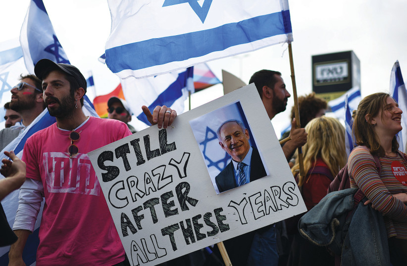 A PROTESTER holds an anti-Netanyahu placard at a mass rally against the judicial reform outside the Knesset on Monday