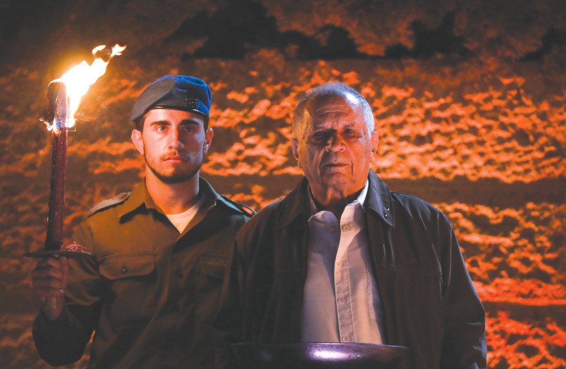  AN IDF soldier holds the flame for a Holocaust survivor to light a torch at Yad Vashem on Holocaust Martyrs and Heroes Remembrance Day, in 2021. (photo credit: OLIVIER FITOUSSI/FLASH90)