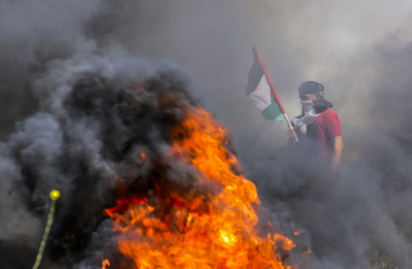  Palestinian demonstrators burn tires during a protest over tension in Jerusalem, at the Israel-Gaza border fence, east of Gaza City April 5, 2023. (photo credit: ATIA MOHAMMED/FLASH90)