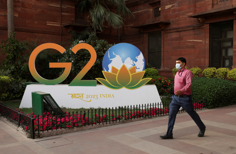  A man walks past a model of G20 logo outside the finance ministry in New Delhi, India, March 1, 2023 (photo credit: REUTERS)