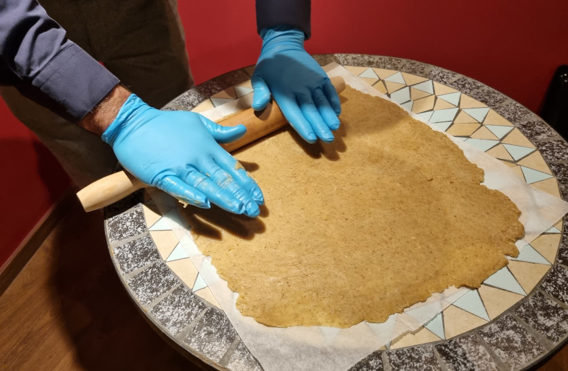  Avi Yefet, caretaker of the Karaite synagogue, rolls out dough to make "massa" for Passover.  (photo credit: MAYA MARGIT/THE MEDIA LINE)