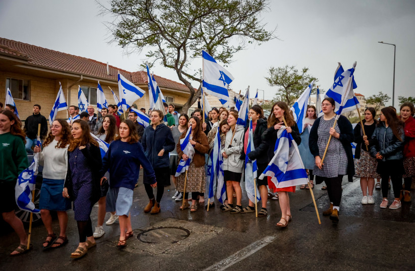  Efrat Residents standing outside their homes with Israeli flags to show solidarity with the Dee family, following the death of Lucy Dee, who died of her wounds three days after the deadly terror attack that killed her two daughters Rina and Maia, in Efrat, in the West Bank, April 10, 2023.  (photo credit: GERSHON ELINSON/FLASH90)