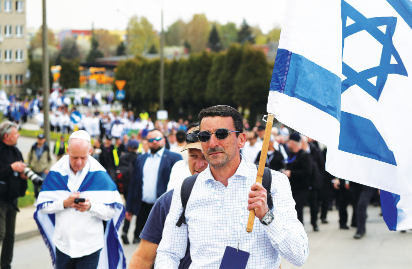  A MAN carries an Israeli flag during the annual March of the Living through the grounds of the former Auschwitz death camp last year. (photo credit: KACPER PEMPEL/REUTERS)