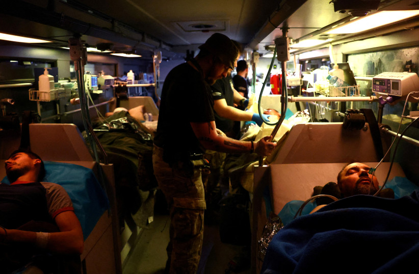  Paramedic Ruslan (26), volunteer with Hospitallers supports an Ukrainian servicemen who was injured in Bakhmut, amid Russia’s attack on Ukraine, during their evacuation in an intensive care unit bus between Bakhmut towards a hospital in Dnipro, Ukraine, April 11, 2023 (photo credit: REUTERS/KAI PFAFFENBACH)