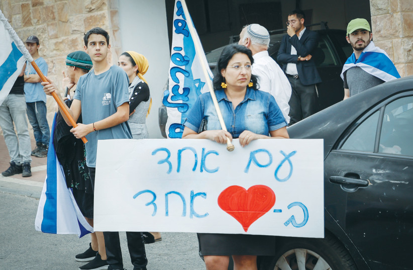 RELATIVES AND friends gather outside the Dee family home in Efrat ahead of the funerals of Maia and Rina. The placard reads: ‘One people with one heart.’  (photo credit: GERSHON ELINSON/FLASH90)