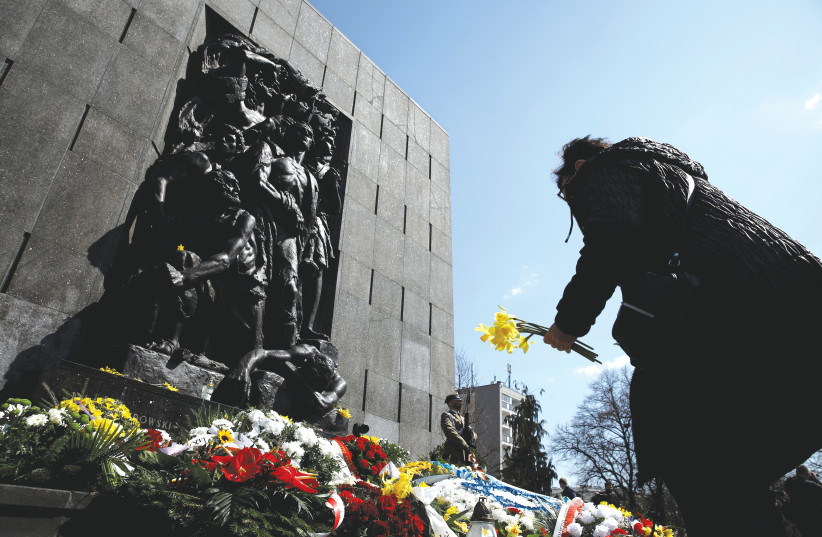  A WOMAN LAYS daffodils during the commemoration of the 78th anniversary of the Warsaw Ghetto Uprising, in front of the Warsaw Ghetto monument in 2021.  (photo credit: KACPER PEMPEL/REUTERS)