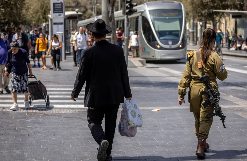 An ultra-Orthodox Jewish man walks next to an Israeli female soldier on Jaffa Road, August 30, 2022 in Jerusalem (photo credit: OLIVIER FITOUSSI/FLASH90)