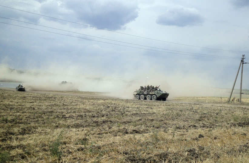 Servicemen sit atop an armoured vehicle as they travel through the steppe near the village of Krasnodarovka in Rostov region August 28, 2014. A Reuters reporter saw on Thursday a column of armoured vehicles and dust-covered troops, one of them with an injured face, driving through the Russian steppe (photo credit: MARIA TSVETKOVA/REUTERS)