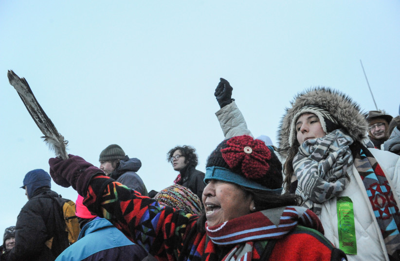 A woman from the Tlingit Tsimphean tribe (C) holds an eagle feather into the air in Oceti Sakowin camp as ''water protectors'' continue to demonstrate against plans to pass the Dakota Access pipeline near the Standing Rock Indian Reservation, near Cannon Ball, North Dakota, U.S. December 3, 2016. (credit: STEPHANIE KEITH/REUTERS)