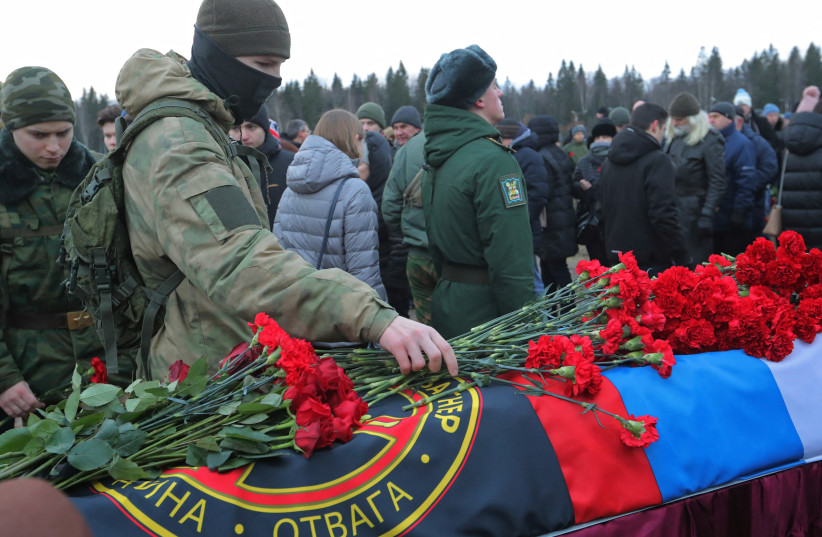  A man places flowers at the coffin during the funeral of Dmitry Menshikov, a mercenary for the private Russian military company Wagner Group, killed during the military conflict in Ukraine, in the Alley of Heroes at a cemetery in Saint Petersburg, Russia December 24, 2022. (credit: REUTERS/IGOR RUSSAK)