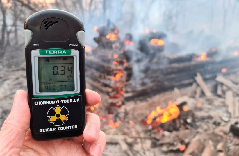 A geiger counter measures a radiation level at a site of fire burning in the exclusion zone around the Chernobyl nuclear power plant, outside the village of Rahivka, Ukraine April 5, 2020. Picture taken April 5, 2020. (photo credit: YAROSLAV YEMELIANENKO/REUTERS)