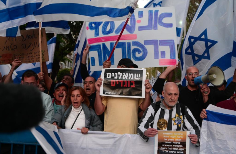  Right-wing protesters demonstrate outside the home of former High Court Chief Justice and Holocaust survivor Aharon Barak. One protester sports a mock Holocaust costume and yellow star, and the other holds a sign reading "leftist traitors," April 30, 2023.  (photo credit: AVSHALOM SASSONI/MAARIV)