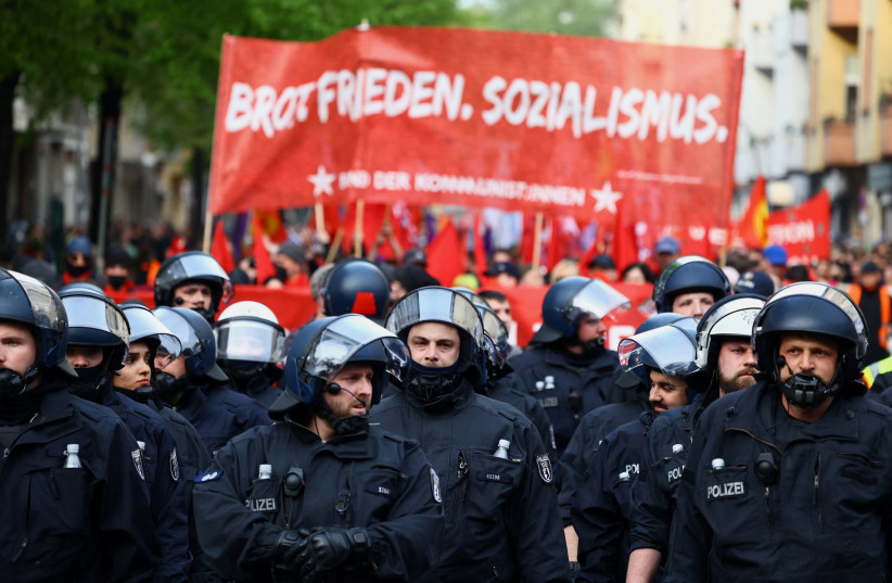 Police officers walk as demonstrators hold banners during a May Day protest in Berlin, Germany, May 1, 2023. (credit: REUTERS/CHRISTIAN MANG)