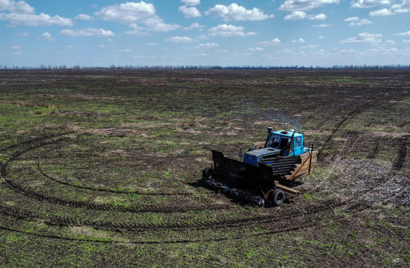 Workers fix a part of a remote controlled demining machine, created by local farmer Oleksandr Kryvtsov with his tractor and armoured plates from destroyed Russian military vehicles near the village of Hrakove, in Kharkiv region, Ukraine April 26, 2023. (credit: REUTERS/Vitalii Hnidyi)