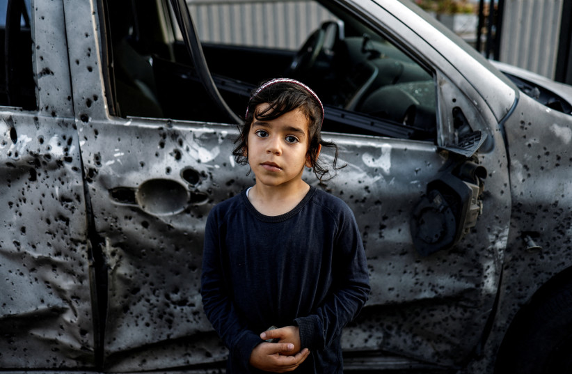 Five-year-old Lavi stands by a car that was damaged by a rocket, launched from Gaza, after it landed in Sderot, southern Israel, May 2, 2023. (credit: AMIR COHEN/REUTERS)
