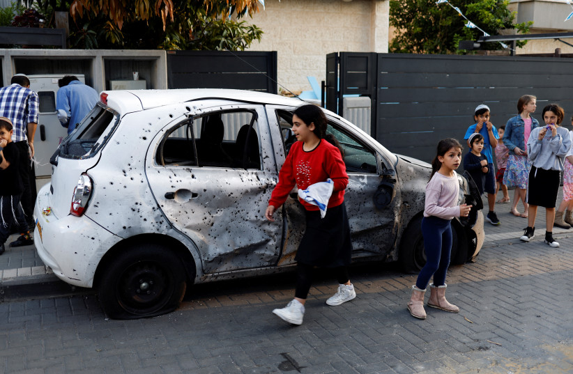 People gather near a car which was damaged after a rocket, launched from Gaza, landed in Sderot, southern Israel, May 2, 2023.  (credit: AMIR COHEN/REUTERS)