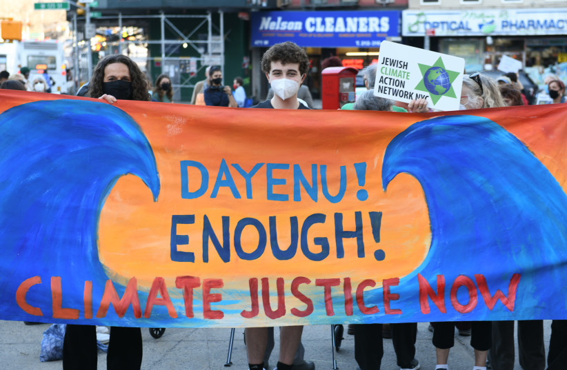  Dayenu CEO Jennie Rosenn holds up a banner after addressing the crowd at a rally urging New York State lawmakers to pass the Climate and Community Investment Act in New York, April 7, 2021. (photo credit: Gili Getz/Courtesy of Dayenu)