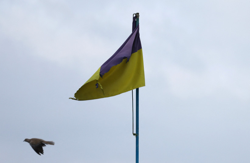  A pigeon flies past a Ukrainian flag on top of the cultural house during heavy fighting at the frontline of Bakhmut and Chasiv Yar, in Chasiv Yar, Ukraine, April 11, 2023.  (credit: KAI PFAFFENBACH/REUTERS)