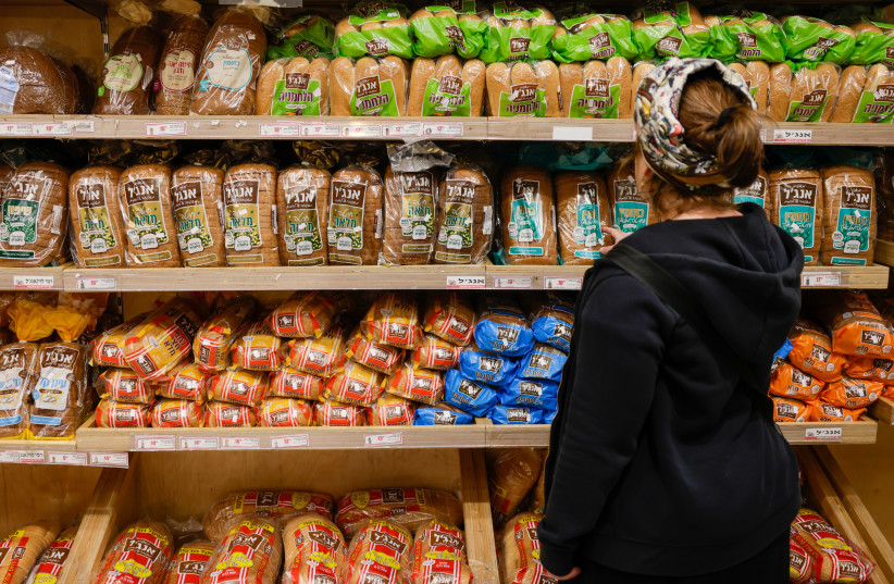 An Israeli is seen picking out 'Angel' bread in a supermarket, May 7, 2023 (credit: MARC ISRAEL SELLEM/THE JERUSALEM POST)