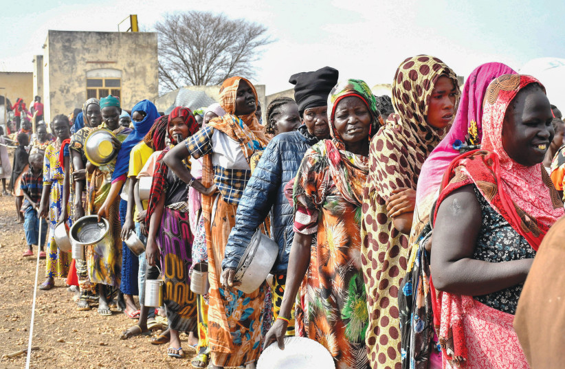  WOMEN WHO fled Sudan following the outbreak of fighting line up to receive food rations at a UN transit center near the border crossing point in South Sudan, last week. (photo credit: Jok Solomun/Reuters)