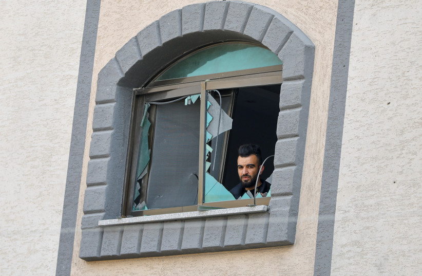  A man looks out of a window damaged in a nearby Israeli strike that killed senior Palestinian Islamic Jihad commander Jihad Ghannam and his wife Wafa, in Rafah, in the southern Gaza Strip May 9, 2023. (photo credit: REUTERS/IBRAHEEM ABU MUSTAFA)
