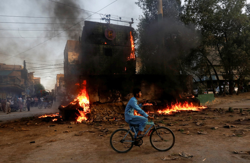  A boy rides past a paramilitary check post, that was set afire by the supporters of Pakistan's former prime minister Imran Khan, during a protest against his arrest, in Karachi, Pakistan May 9, 2023. (credit: Akhtar Soomro/Reuters)