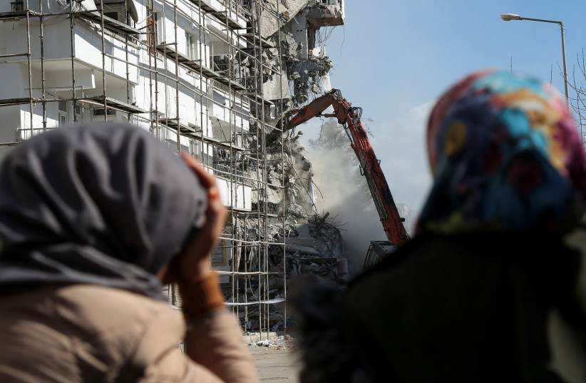  A woman reacts as she watches the demolition of a damaged building after a deadly earthquake in Diyarbakir, Turkey February 21, 2023.  (credit: Sertac Kayar/Reuters)