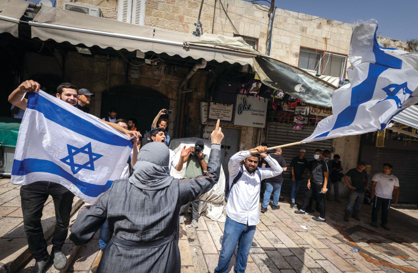  JEWISH MARCHERS wave the Israeli flag in front of an Arab woman in the Muslim Quarter of the Old City, on Jerusalem Day last year (photo credit: OLIVIER FITOUSSI/FLASH90)