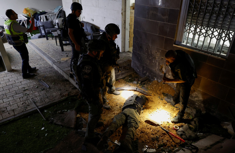  Police officers work to retrieve a rocket, fired from Gaza, that landed near a home in Sderot, Israel May 10, 2023 (photo credit: REUTERS/AMMAR AWAD)