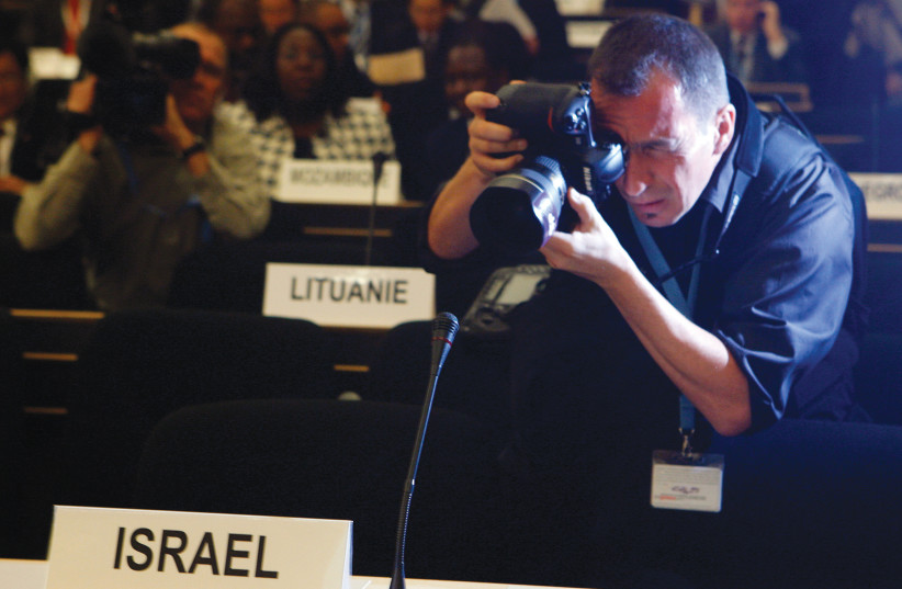  PHOTOGRAPHING THE Israeli delegation’s empty seats at the UN-sponsored conference on racism in 2009 – empty to protest the bias against Israel.  (photo credit: DENIS BALIBOUSE/REUTERS)