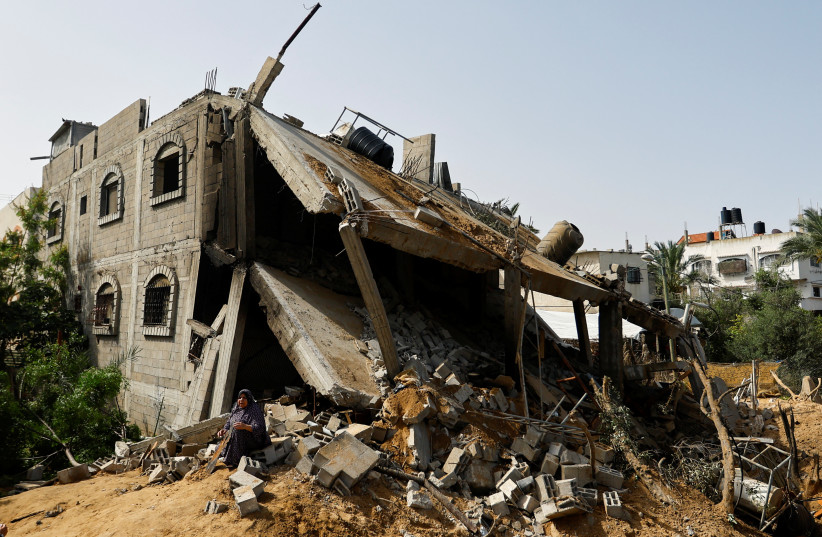 Palestinian woman, Fatma Basheer, sits beside the remains of her house which was destroyed in Israeli air strikes, in Deir al-Balah town in the central Gaza Strip, May 12, 2023. (credit: IBRAHEEM ABU MUSTAFA/REUTERS)