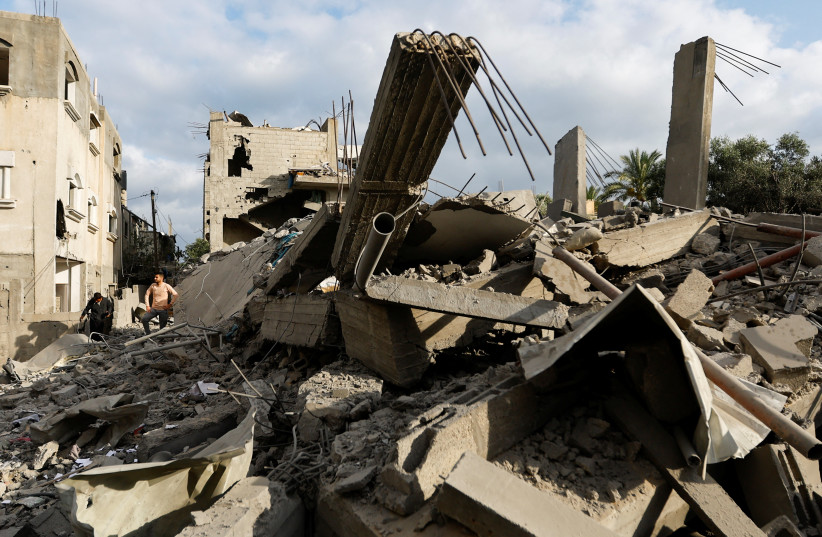  Palestinians gather at the site of an Israeli airstrike amid Israel-Gaza fighting in Deir al-Balah town in the central Gaza Strip, May 13, 2023. (credit: REUTERS/IBRAHEEM ABU MUSTAFA)
