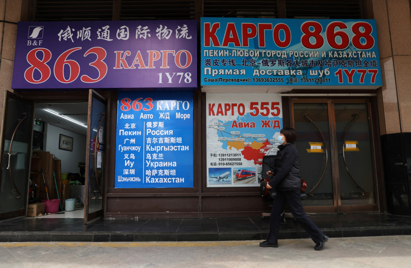 A person walks past offices with signs promoting logistics services to Russia and other former Soviet republics, at a trading centre in Beijing, China April 1, 2022 (credit: REUTERS/TINGSHU WANG)