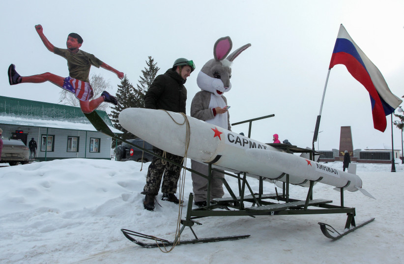 Participants stand next to a sled, which is composed of various parts including elements depicting Ukraine's President Volodymyr Zelenskiy and Russian missiles Kinzhal and Sarmat (photo credit: REUTERS/ALEXEY NASYROV)