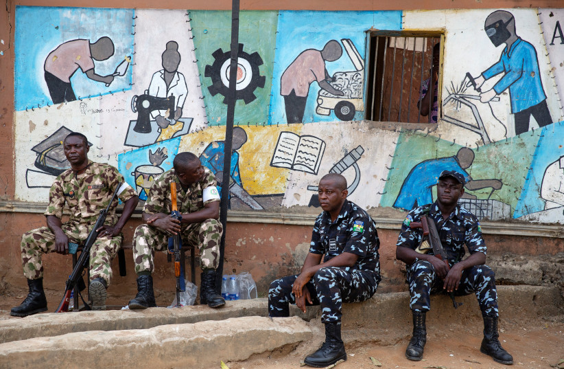  A day after the elections, soldiers and police guard the entrance to a vote collation centre that had been stormed earlier in the day by unknown assailants, some of who were apprehended in Alimosho, Lagos, Nigeria on February 26, 2023 (photo credit: REUTERS)