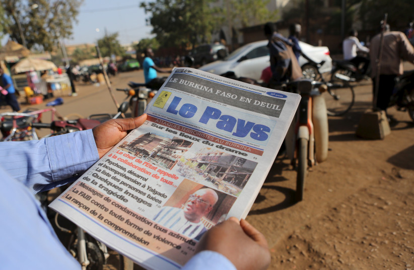A man reads newspaper headlines that talk about the al Qaeda attack on the Splendid Hotel and Cappuccino that killed at least 28 people from at least seven countries in Ouagadougou, Burkina Faso, January 18, 2016. (credit: JOE PENNEY/ REUTERS)