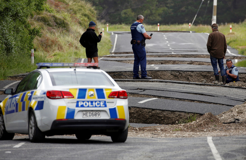  Policemen and locals look at damage following an earthquake, along State Highway One near the town of Ward, south of Blenheim on New Zealand's South Island, November 14, 2016 (credit: REUTERS/ANTHONY PHELPS/FILE PHOTO)