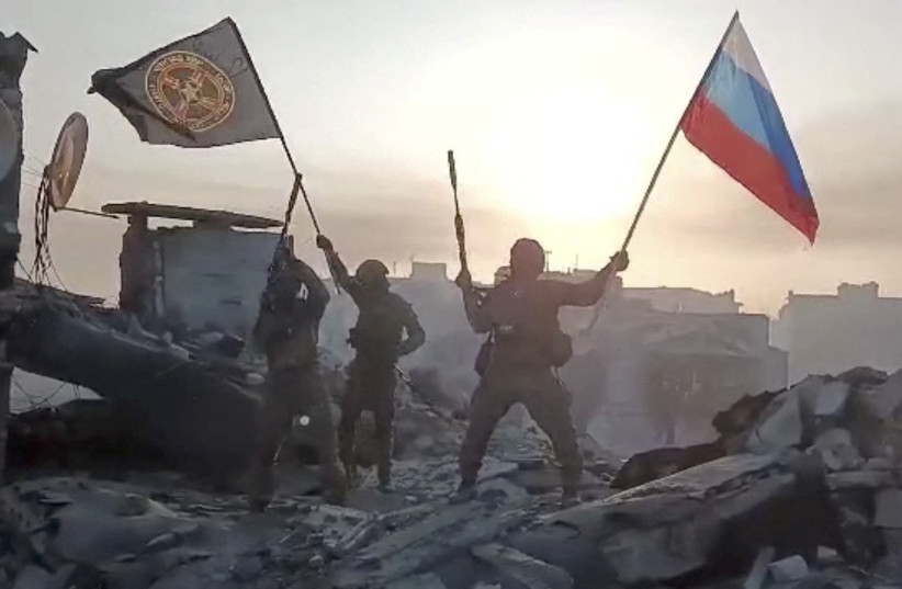 Wagner mercenary group fighters wave flags of Russia and Wagner group on top of a building in an unidentified location, in the course of the Russia-Ukraine conflict, in this still image obtained from a video released on May 20, 2023. (photo credit: PRESS SERVICE OF "CONCORD"/HANDOUT VIA REUTERS)
