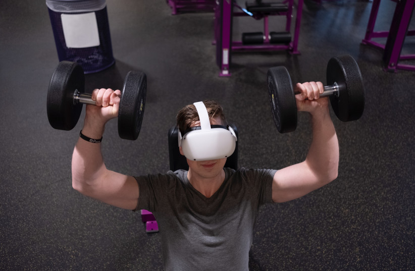  A man lifting weights while wearing a virtual reality headset. (photo credit: Eugene Capon/Pexels)