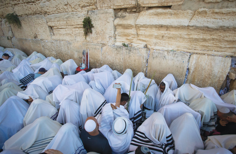  AFTER COVERING their heads with ‘tallitot,’ the Kohanim raise their hands to bless the congregation (Pictured: On Sukkot at the Western Wall) (photo credit: FLASH90)