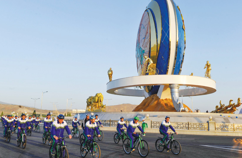  FOREIGN MINISTER Eli Cohen made Israel’s first ministerial visit in decades to Turkmenistan, meeting with President Gurbanguly Berdymukhamedov last month. Pictured: Cyclists ride past a monument promoting a healthy lifestyle in Ashgabatwere.  (photo credit: Igor Sasin/AFP via Getty Images)