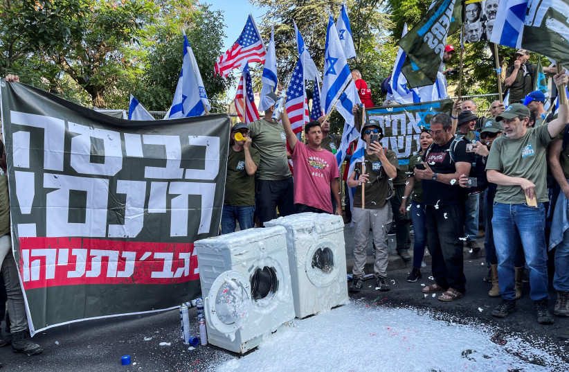  Members of Israel's military reservists hold a banner with the words ''free laundry for Mrs. Netanyahu'' as part of a stunt outside of Israeli Prime Minister Benjamin Netanyahu's residence to demonstrate against his coalition government's judicial overhaul, in Jerusalem May 25, 2023. (credit: ILAN ROSENBERG/REUTERS)